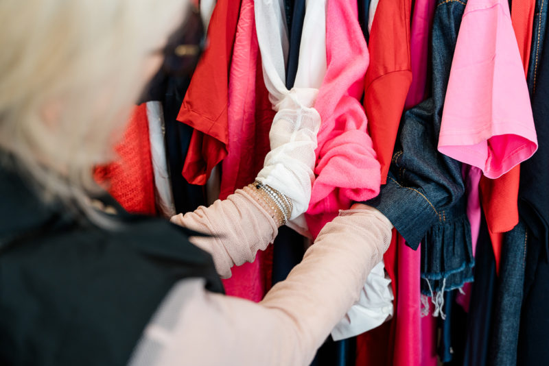 Hand mit weißem Spitzenhandschuh knüpft einen roten Schal um ein Kleidungsstück